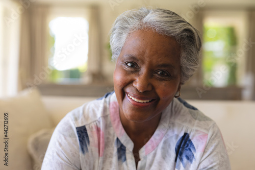 Portrait of senior african american woman sitting on sofa looking at camera and smiling