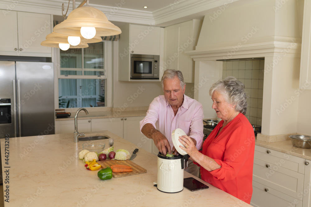 Senior caucasian couple cooking together and talking in kitchen Senior caucasian couple cooking together and talking in kitchen