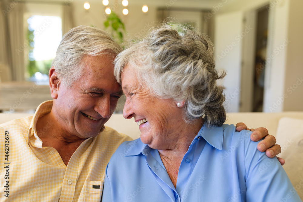 Senior caucasian couple sitting on sofa embracing and smiling Senior caucasian couple sitting on sofa embracing and smiling