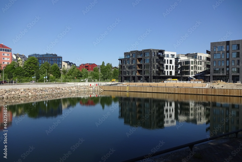 New modern building with new flats or apartments construction in a new district in Kalamaja, Kopli, Tallinn, Estonia. Reflection of buildings in a blue water canal. A sunny summer day with aclear sky.