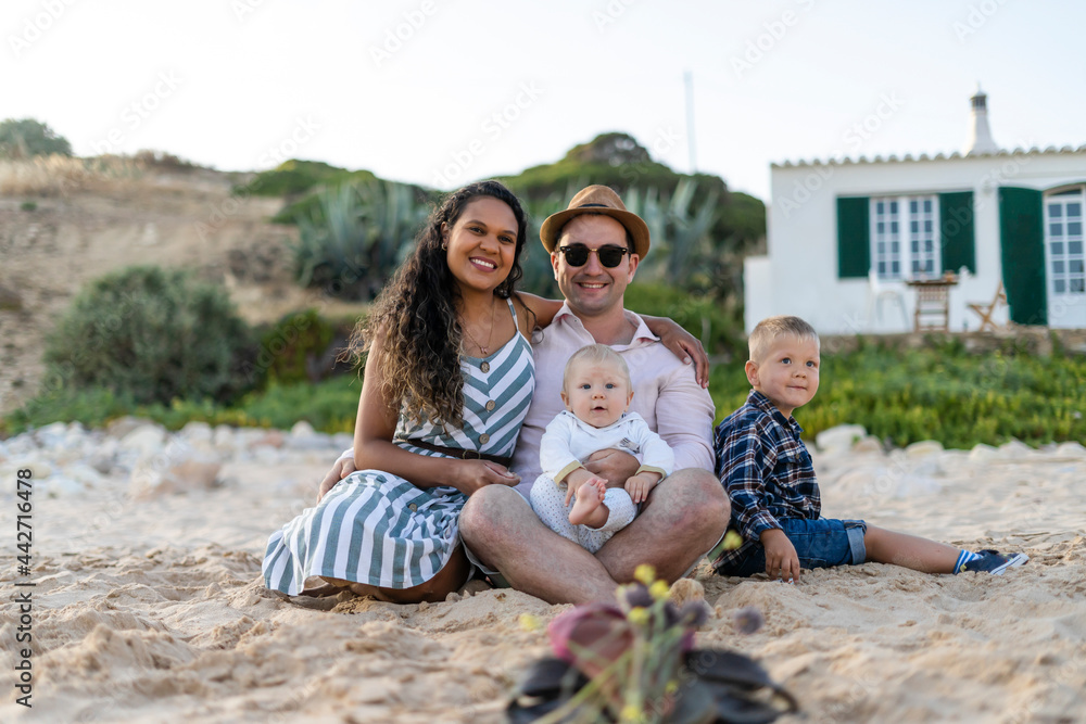 The family with two small boys sitting and posing on the beach