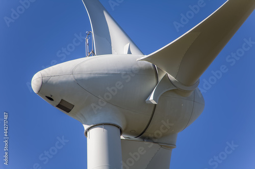 Detailed close up view of a wind turbines; generator, rotor and blade view on blue sky background