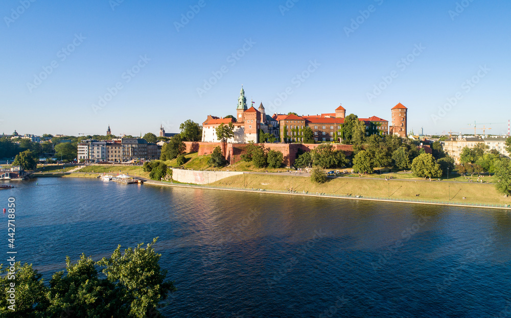 Krakow, Poland. Aerial panorama at sunset with Royal Wawel castle and cathedral. Vistula river bank, trees, park, promenade and walking people