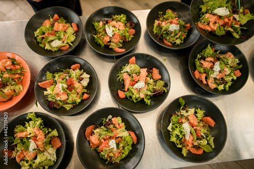 top view of bowls of tasty salmon salad with arugula and other greens