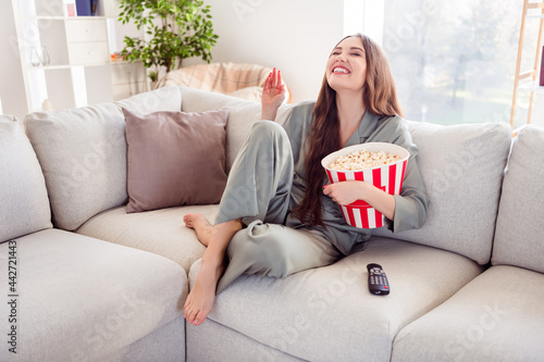 Full size profile side photo of young girl happy positive smile laugh watch comedy weekend rest relax eat popcorn indoors