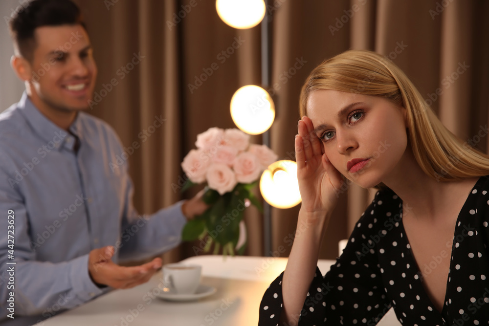 Man giving flowers to displeased young woman in restaurant. Failed first date Man giving flowers to displeased young woman in restaurant. Failed first date