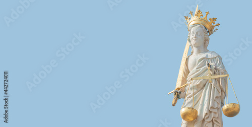 Banner with ancient statue of goddess Justice with sword and scale isolated at the roof top decoration of Doge's Palace in Venice, Italy, summer time, blue sky background, closeup