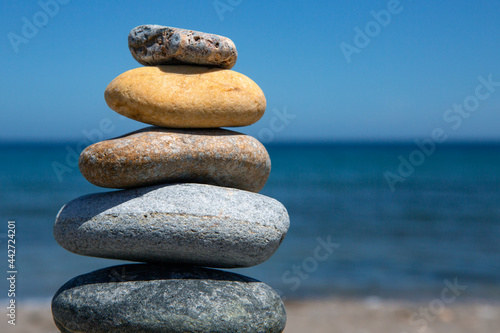 Pile of stones of different shapes and colors in balance, with the background of the sea out of focus