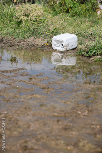 Foto Plastic recipient pouring chemical products in the water.