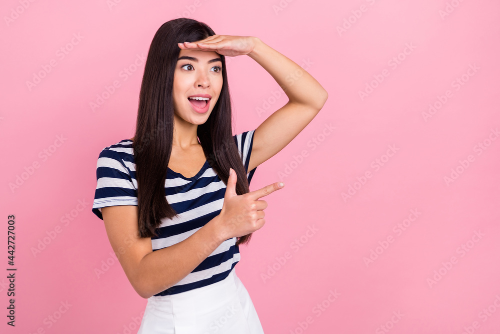 Photo of impressed long hairdo young millennial lady look point empty space wear striped t-shirt isolated on pastel pink color background Photo of impressed long hairdo young millennial lady look point empty space wear striped t-shirt isolated on pastel pink color background