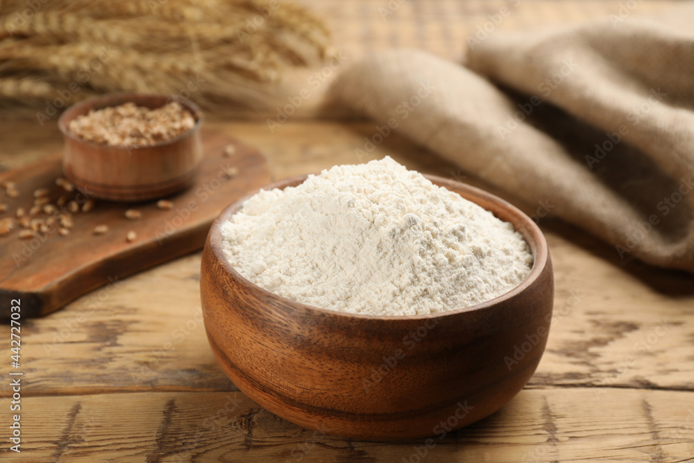 Wheat flour in bowl on wooden table Wheat flour in bowl on wooden table