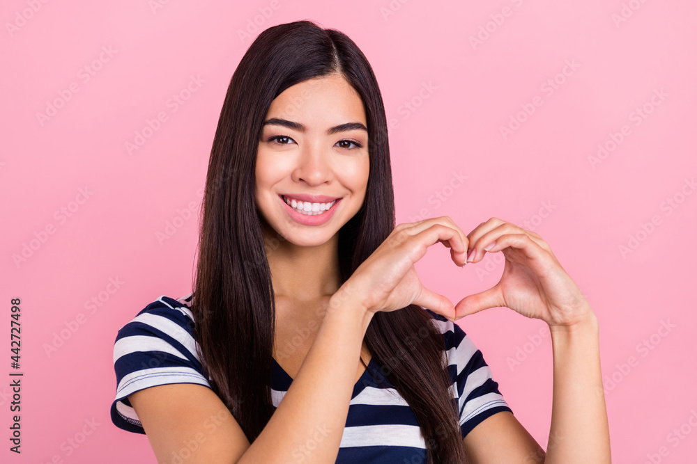 Photo of excited charming young lady dressed striped clothes smiling showing fingers heart isolated pink color background Photo of excited charming young lady dressed striped clothes smiling showing fingers heart isolated pink color background