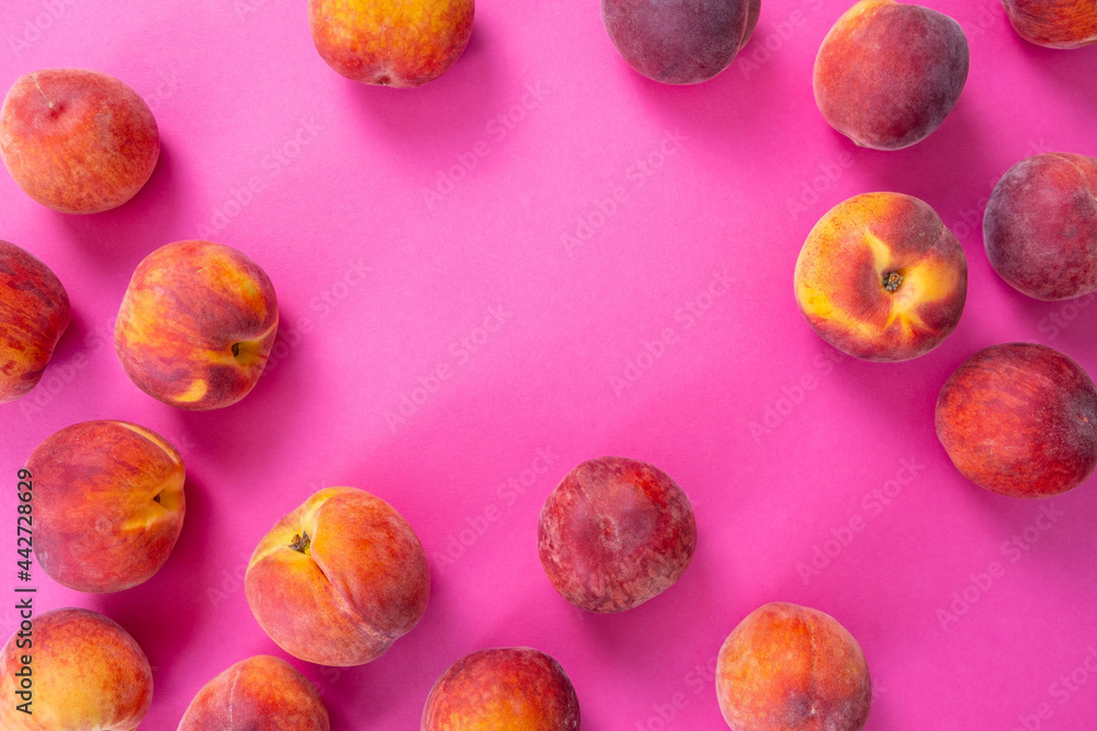 scattered ripe peaches, lies on a pink background scattered ripe peaches, lies on a pink background
