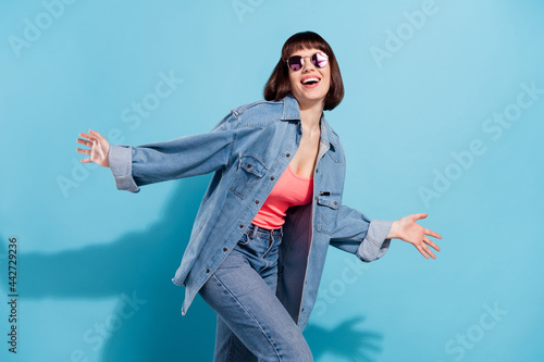Portrait of attractive carefree cheerful girl dancing having fun spending free time isolated over bright blue color background