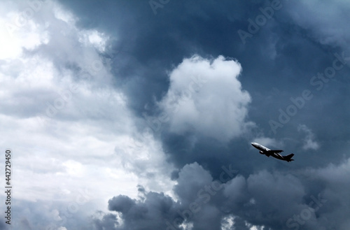 Black and white photo of plane taking off against the background of storm clouds.