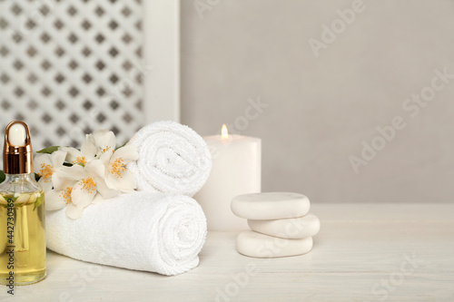 Composition with spa stones and beautiful jasmine flowers on white wooden table  space for text