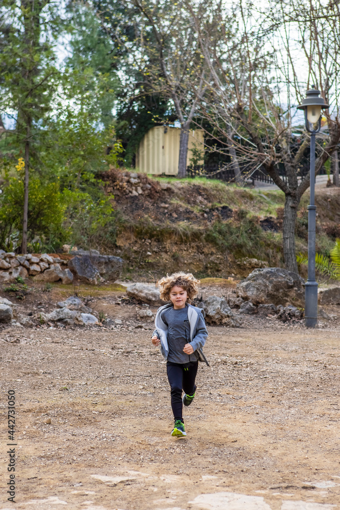 Boy running on dry terrain against trees Boy running on dry terrain against trees