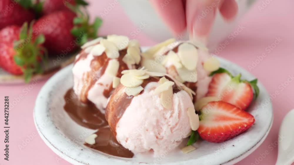 Serving strawberry ice cream with chocolate sauce and almond flakes. Summer dessert, ice cream sundae Serving strawberry ice cream with chocolate sauce and almond flakes. Summer dessert, ice cream sundae