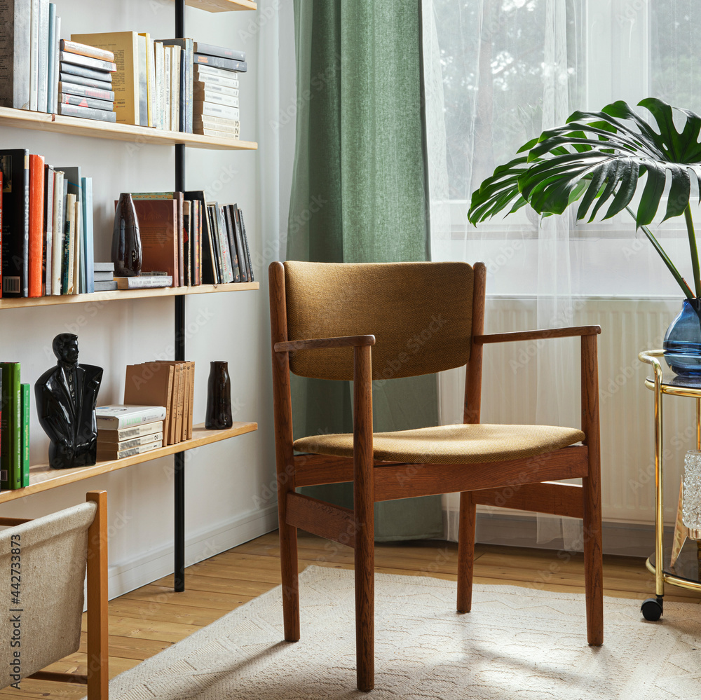 Fototapeta premium Stylish composition of home office interior with design retro chair, home library, plant, window, books, decoration and elegant personal accessories in home decor.