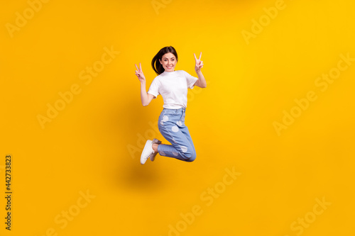 Full body profile side photo of young girl happy positive smile show peace cool v-sign isolated over yellow color background