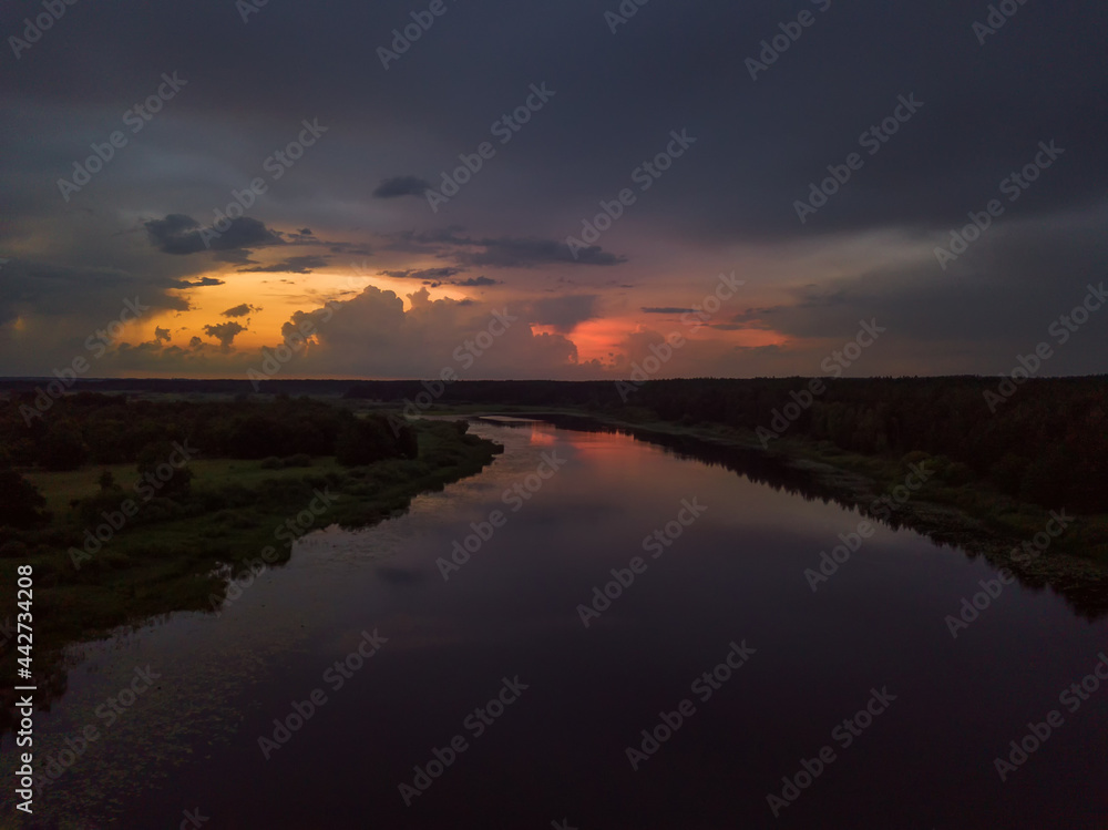 Beautiful, fascinating sunset with clouds over a lake, a river on a summer evening, view from a drone