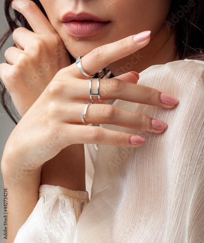 Beautiful young girl posing hand wearing rings and jewellery touching her chin and lip