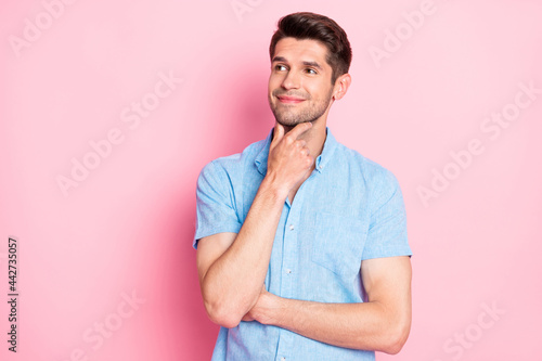 Portrait of attractive cheerful pensive guy thinking copy space touching chin isolated over pink pastel color background