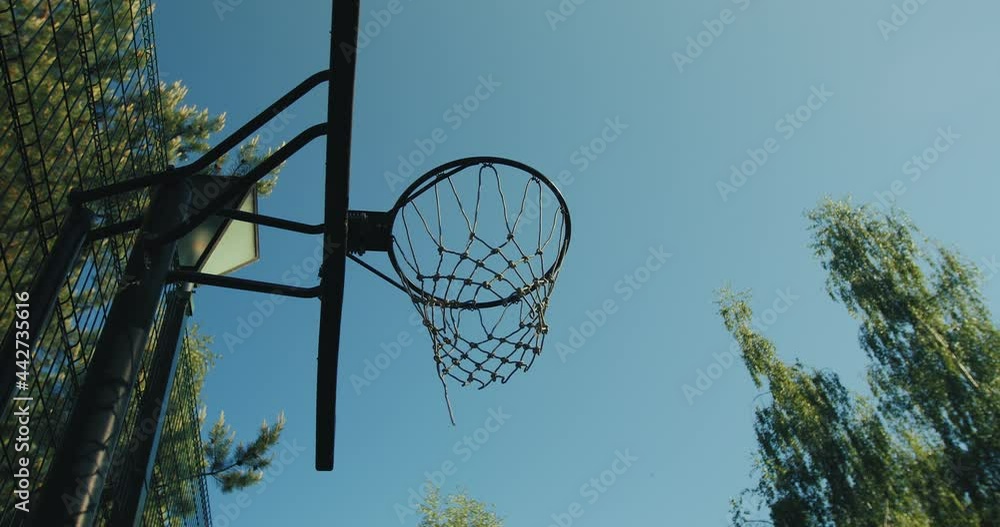 Basketball ball flying into basketball hoop on court outdoors in summer