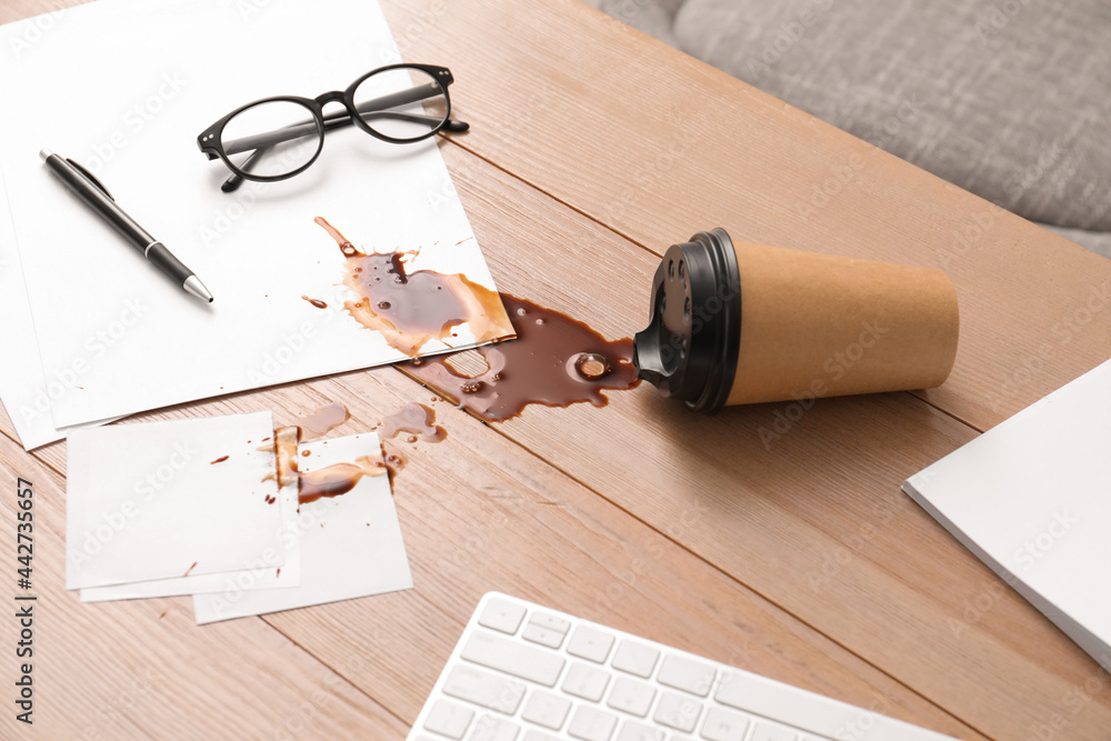 Fototapeta premium Paper cup with coffee spill on wooden office desk