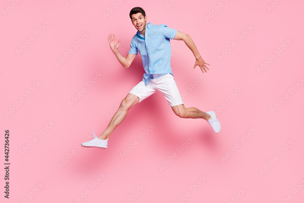 Profile photo of hurry fast sportive man jump run wear blue shirt shorts sneakers isolated on pink color background Profile photo of hurry fast sportive man jump run wear blue shirt shorts sneakers isolated on pink color background