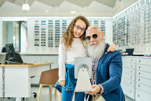 Smiling grandfather and granddaughter in optical store photo