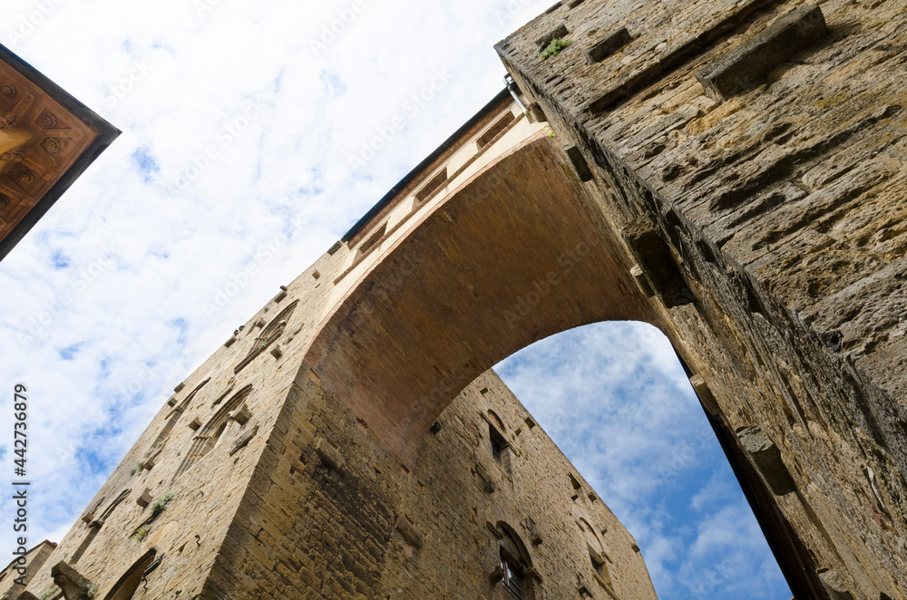 Bottom view of a tall ancient arch and blue sky with clouds
