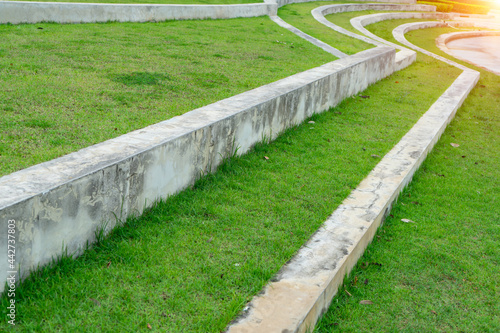 Concrete curb along and curve on the grass lawn that make to the boundary and step for rain the water at the park.
