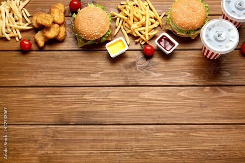 Flat lay composition with delicious fast food menu on wooden table. Space for text