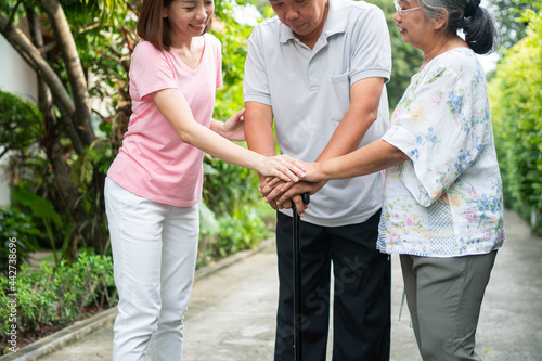 Happy family walking together in the garden. Old elderly using a walking stick to help walk balance. Concept of  Love and care of the family And health insurance for family © Prot