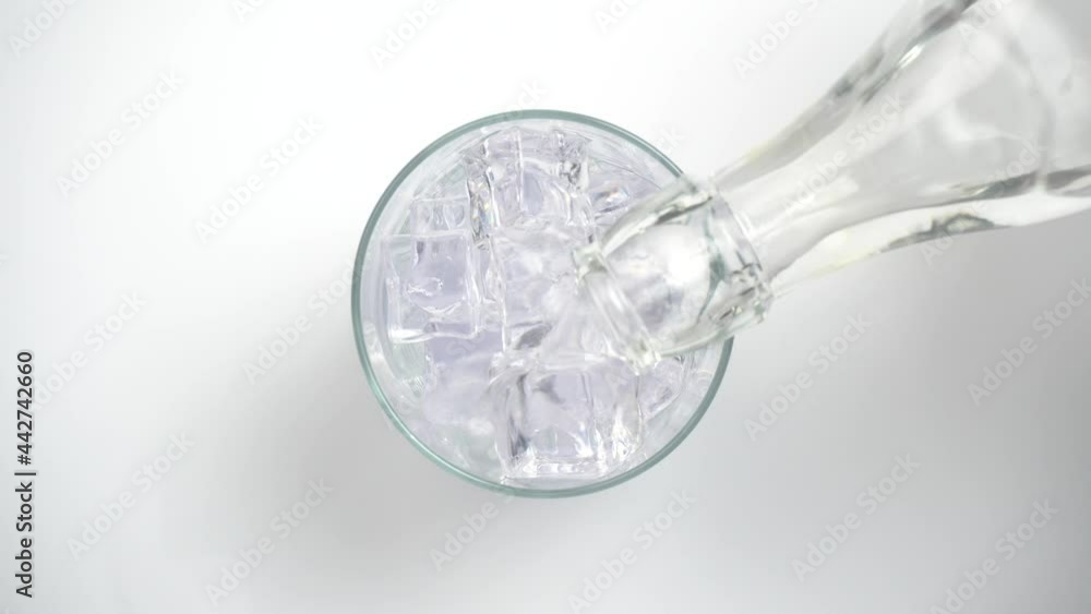 Vertiendo refresco de tónica o bebida con gas en un vaso con hielos, vista desde arriba