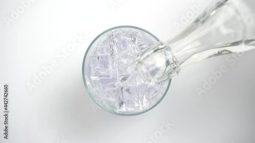 Vertiendo refresco de tónica o bebida con gas en un vaso con hielos, vista desde arriba photo