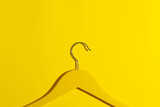 Yellow wooden hanger on yellow background in close-up