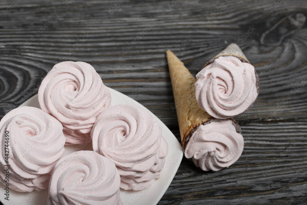 Marshmallow on a plate. Waffle cones with zephyr. On brushed pine boards.