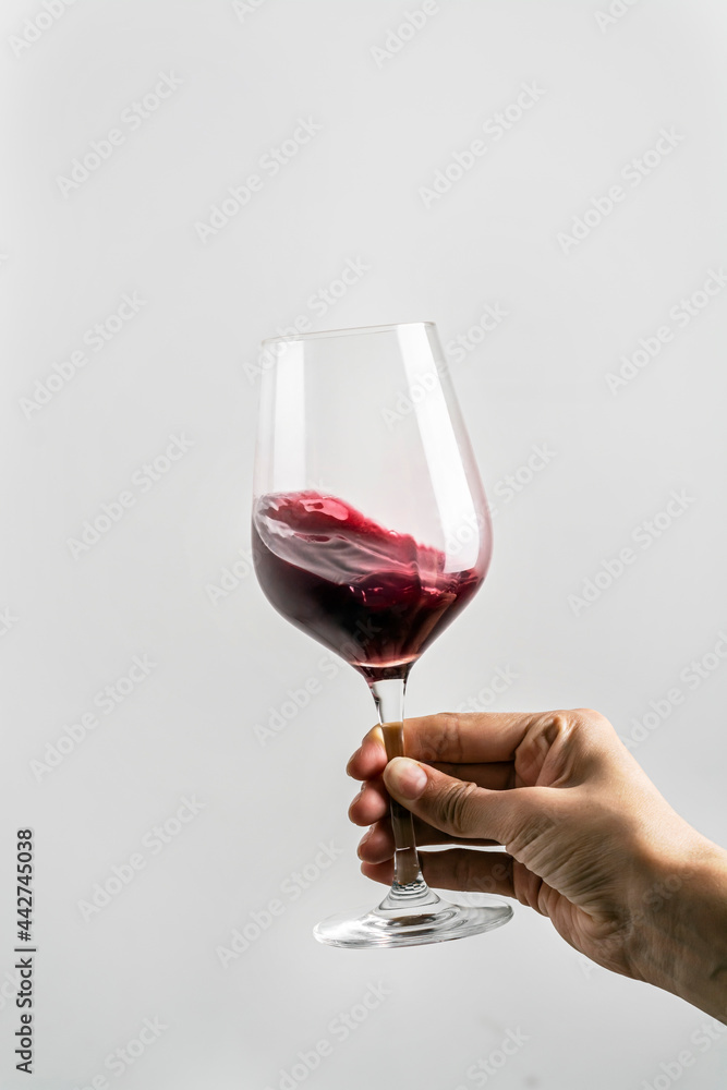 
female hand swinging wineglass on white background.