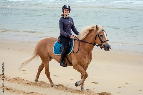 pretty young woman riding a horse on the beach