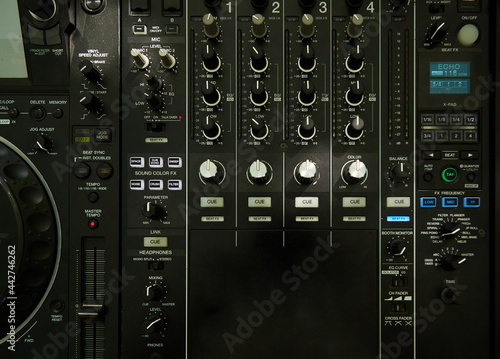 Upper view closeup of dj musical mixer professional console black color with many buttons and knobs in night club or studio on digital background, horizontal picture