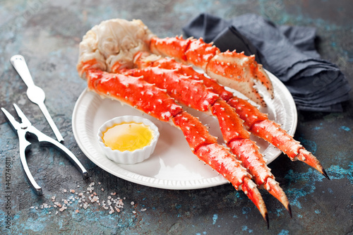 Red king crab legs with butter sauce on a plate, selective focus photo