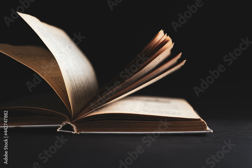 Open book with pages on a black background.