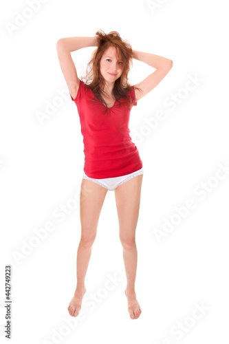 Portrait of a smiling young woman wearing a red top and panties, isolated on white studio background © Jochen Schönfeld
