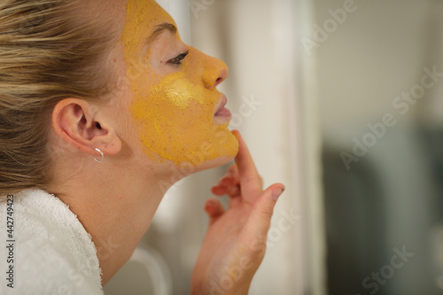 Wallpaper Mural Caucasian woman in bathroom wearing bathrobe, looking in mirror and applying face mask Torontodigital.ca