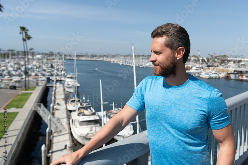 Handsome man vacationer stand at bridge railing over river summer outdoors, vacation