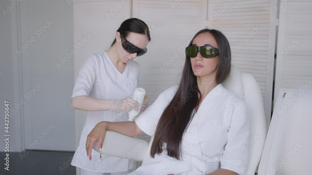 Procedure of removing hairs on hand. Laser hair removal on a diode laser, tracking moving camera. Woman cosmetologist applies laser hair removal gel on female hand. photoepilation, body care concept. Procedure of removing hairs on hand. Laser hair removal on a diode laser, tracking moving camera. Woman cosmetologist applies laser hair removal gel on female hand. photoepilation, body care concept.