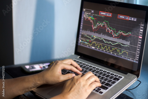 Man presses laptop keyboard to view stock market and analysis graph