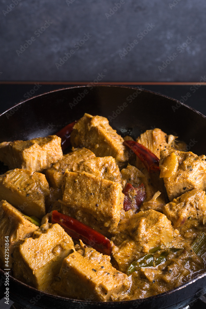 cooking jackfruit curry dish, tempering with oil and coconut milk, classic sri lankan vegetarian dish on a pan, closeup view - obrazy, fototapety, plakaty 